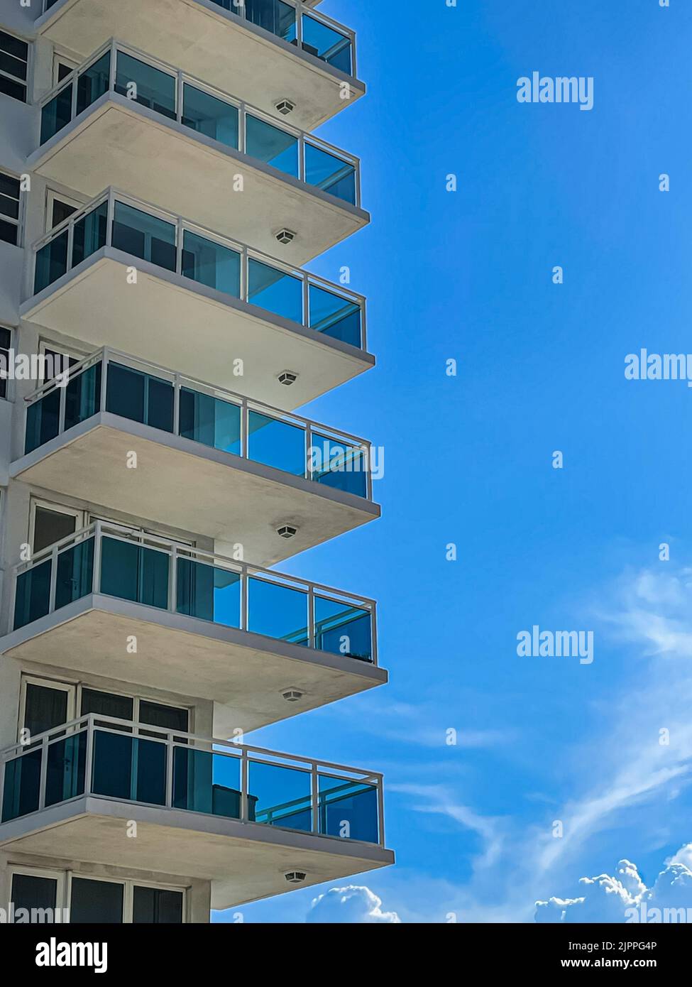 Los altos patios del condominio están apilados uno encima del otro contra un cielo azul cobalto del sur de Florida. Foto de stock