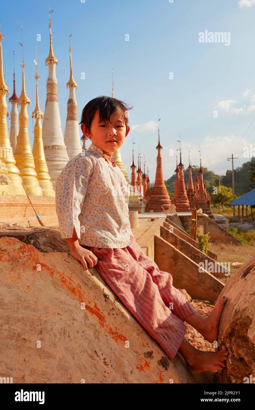 Retrato de una niña birmana con las estupas de la pagoda Shwe Indein al fondo, Lago Inle, Myanmar (Birmania). Foto de stock