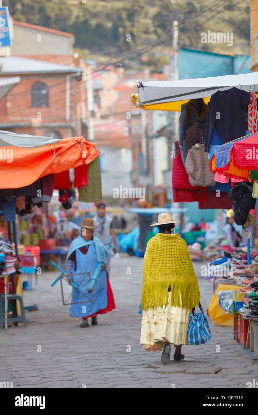 Cholas bolivianas con ropa tradicional colorida caminando en un mercado callejero, Copacabana, Lago Titicaca, provincia de La Paz, Bolivia. Foto de stock