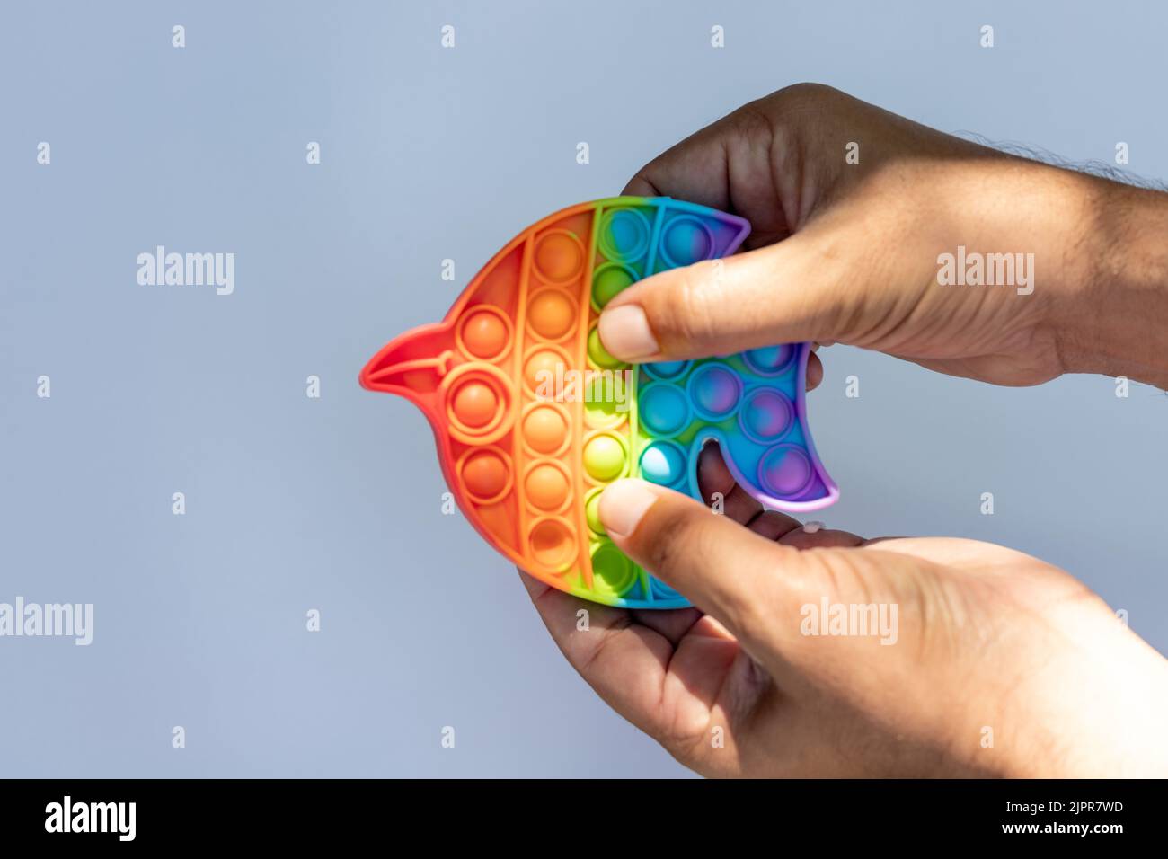 pulsar un juguete sensorial antiestrés colorido push pop juego en las manos Foto de stock