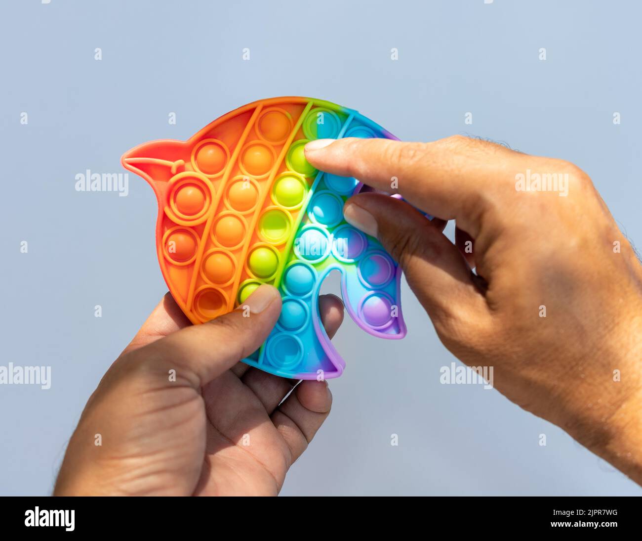 Sujetando en la mano y jugando contra el estrés pop juego de juguete Foto de stock