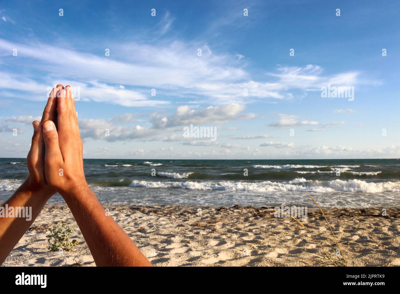 Gesto de Namaste sobre fondo aéreo. Rezando manos en el fondo del paisaje marino. Orar y esperar concepto. Oren por la paz. Foto de stock