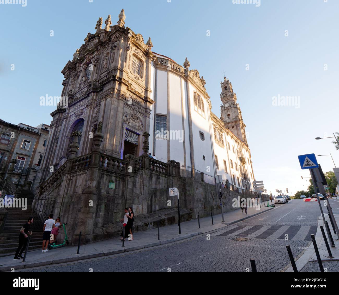 Mirando por el lado del exterior de la Iglesia Barroca de los Clérigos, Oporto, Portugal en una noche de verano mientras los peatones caminan por allí. Foto de stock