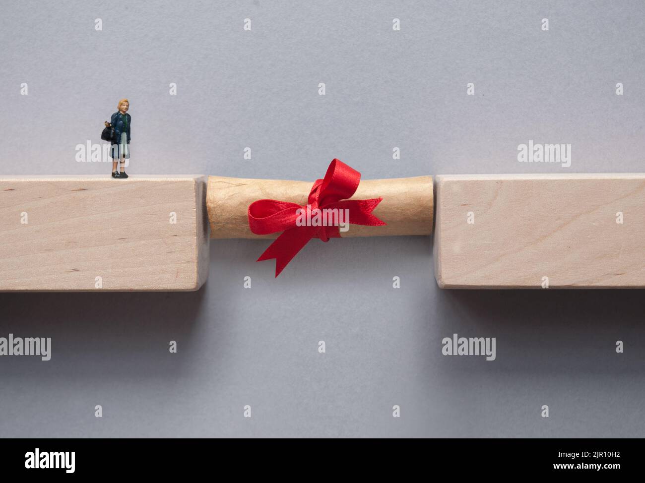 La graduación scroll puenteando el hueco entre los bloques de madera para la figura miniatura hembra para cruzar Foto de stock