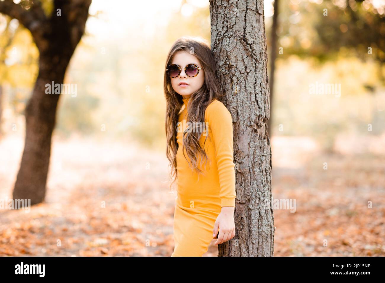 Lindo niño con estilo niña de 4-5 usa vestido de punto amarillo gafas de sol posando en el parque al aire Temporada de otoño. Infancia Fotografía de stock - Alamy