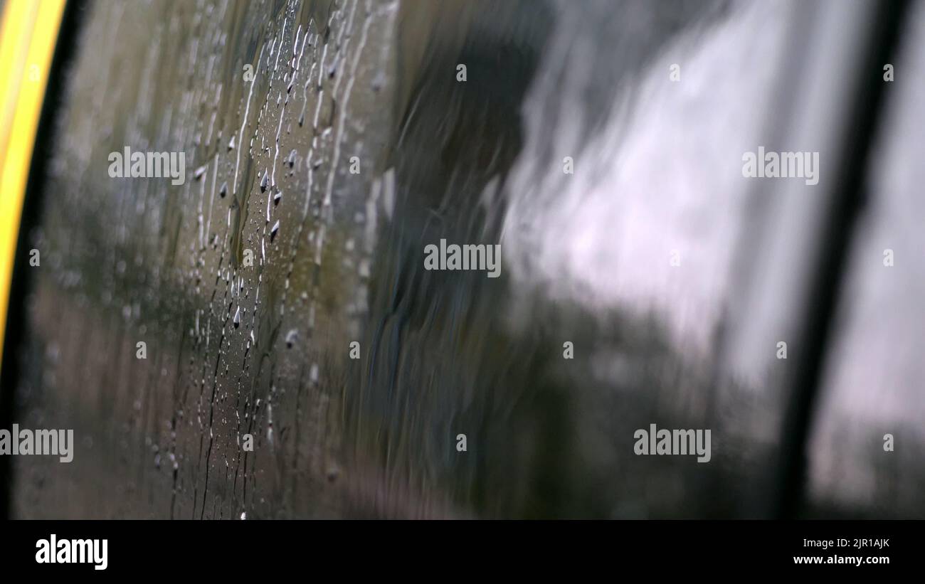 primer plano, en las ventanas de cristal del coche, las gotas de lluvia caen por una multitud de riachuelos. llueve mucho, agujerea. gotas de lluvia en el cristal del coche. Fotografía de alta calidad Foto de stock