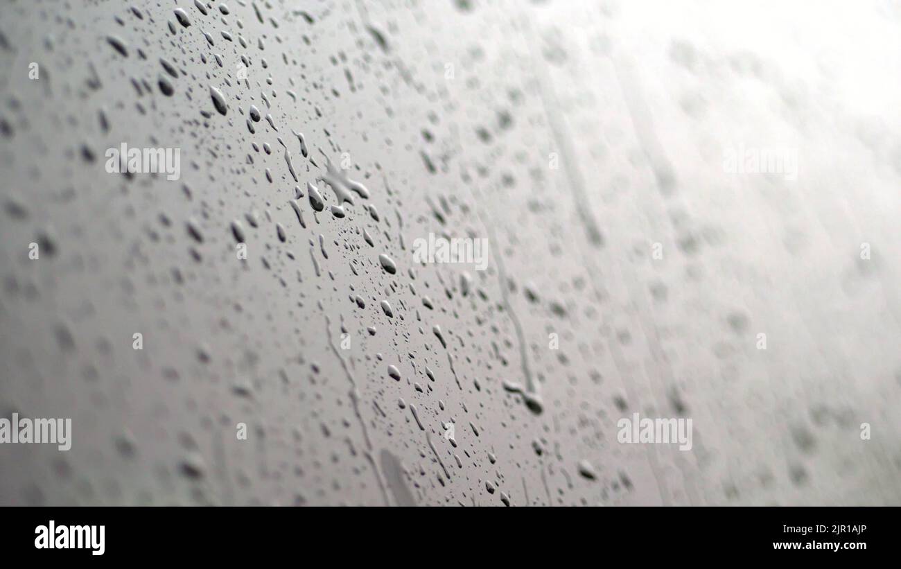 primer plano, en las ventanas de cristal del coche, las gotas de lluvia caen por una multitud de riachuelos. llueve mucho, agujerea. gotas de lluvia en el cristal del coche. Fotografía de alta calidad Foto de stock