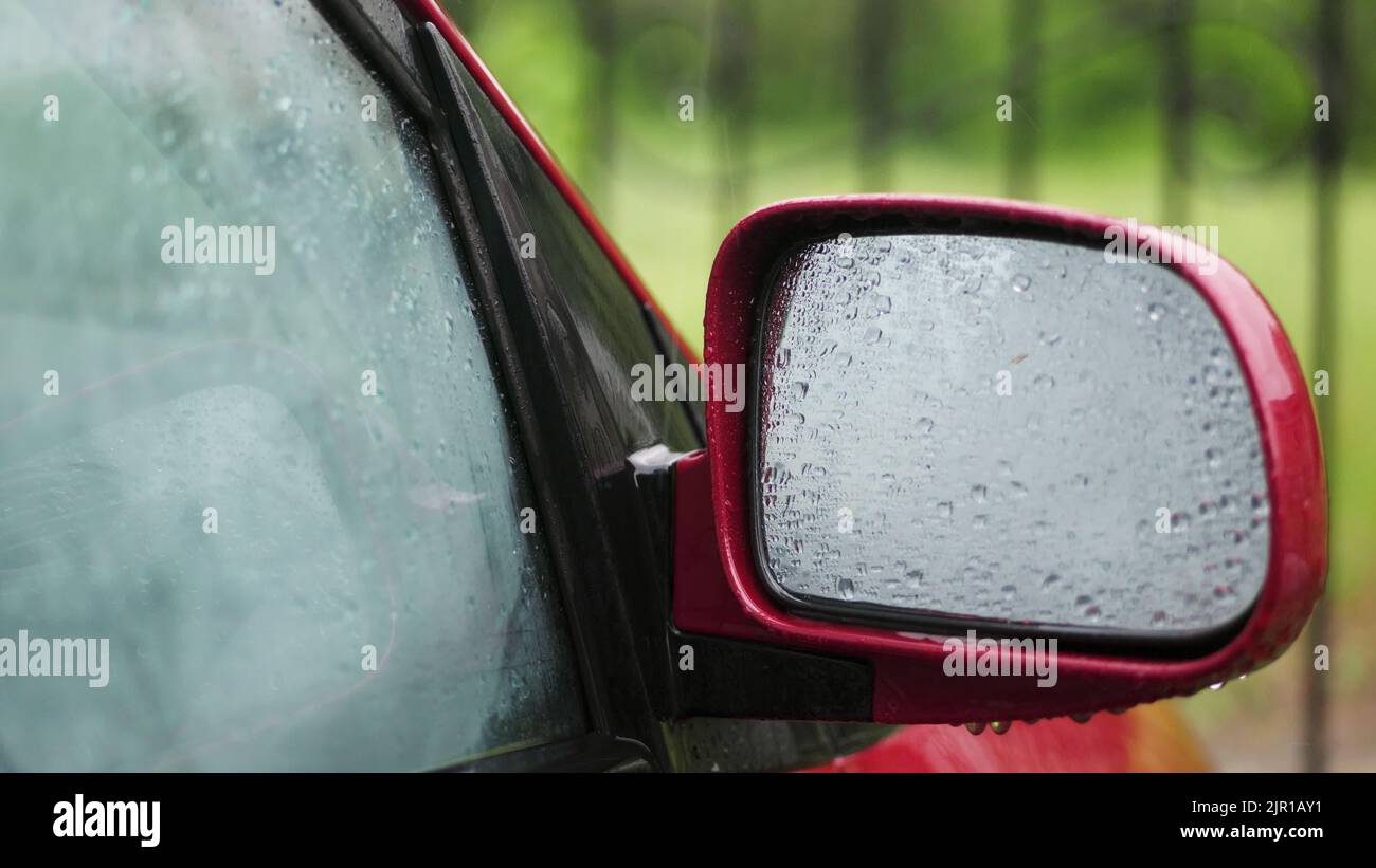 primer plano, en las ventanas de cristal del coche, las gotas de lluvia caen por una multitud de arroyos. gotas de lluvia en el espejo de la vista lateral. Hay mucha lluvia, una ducha y gotas de lluvia en el cristal del coche. Fotografía de alta calidad Foto de stock