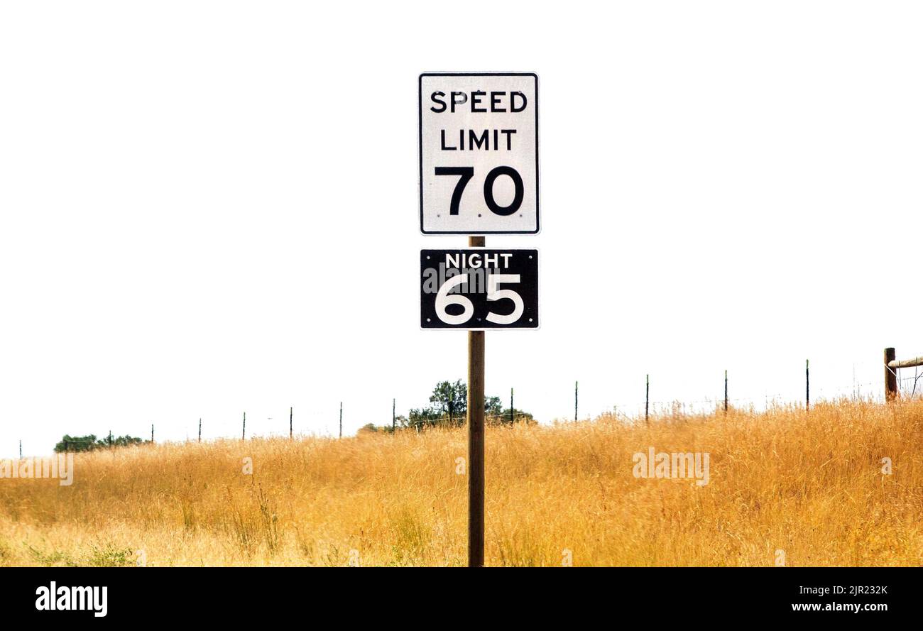 Señales de límite de velocidad diurnas y nocturnas colocadas a lo largo de una carretera rural en Montana, Estados Unidos Foto de stock
