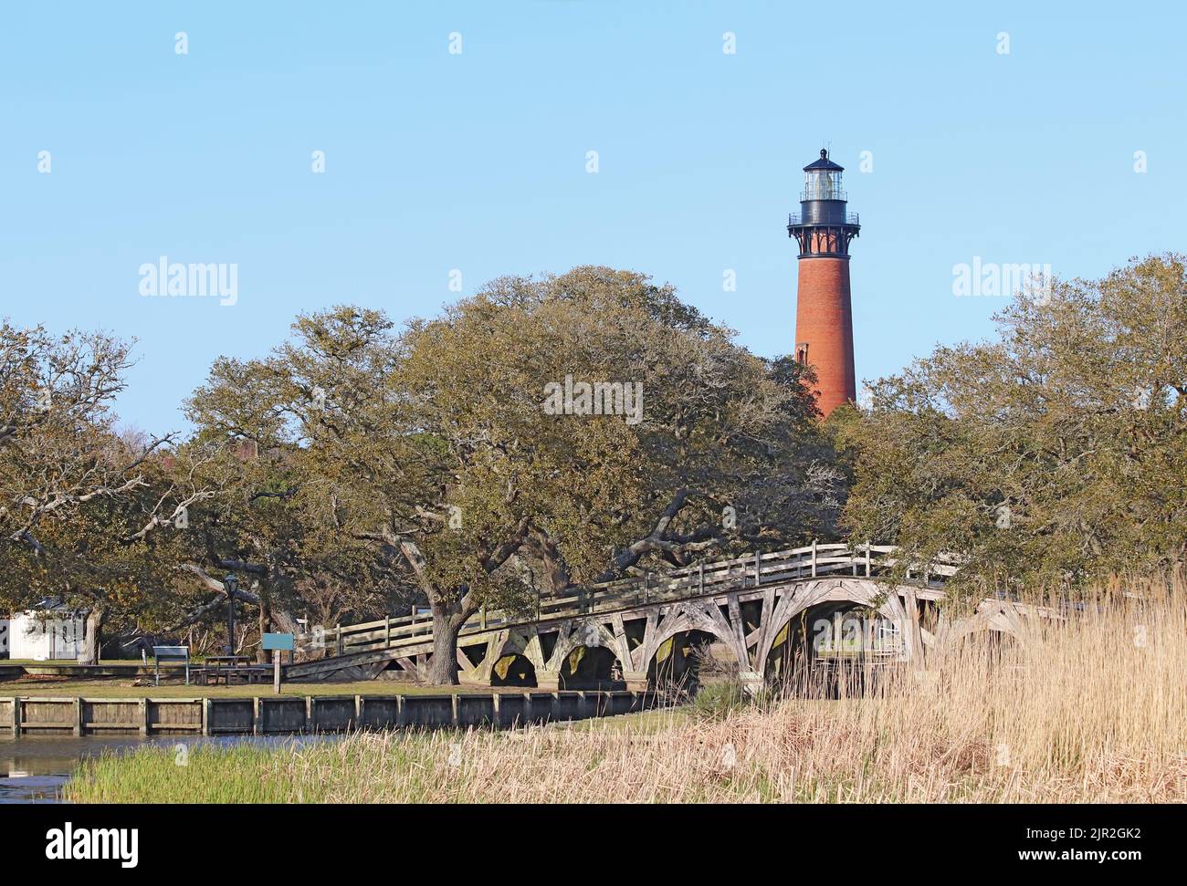 La estructura de ladrillo rojo del faro de Currituck Beach se eleva sobre un puente de madera sobre parte del Sound cerca de Corolla, Carolina del Norte Foto de stock