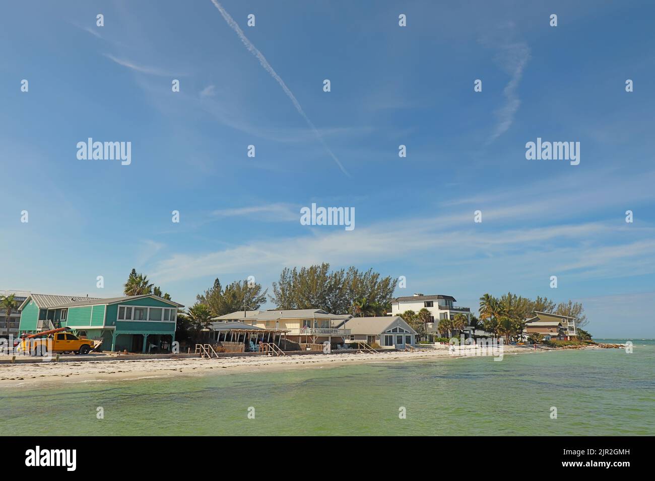 Horizonte de casas a lo largo de la playa en Bean Point en el extremo norte de la Isla Anna Maria, Florida, con gente irreconocible caminando en la arena Foto de stock