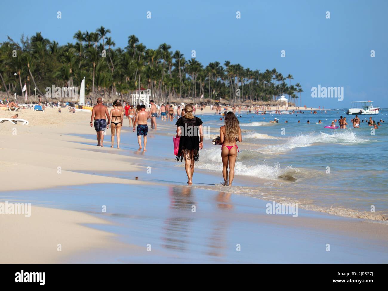 La gente caminando por la arena sobre el fondo de las palmeras de coco, las niñas en bikini en primer plano. Vacaciones en playa tropical, turistas en resort océano Foto de stock