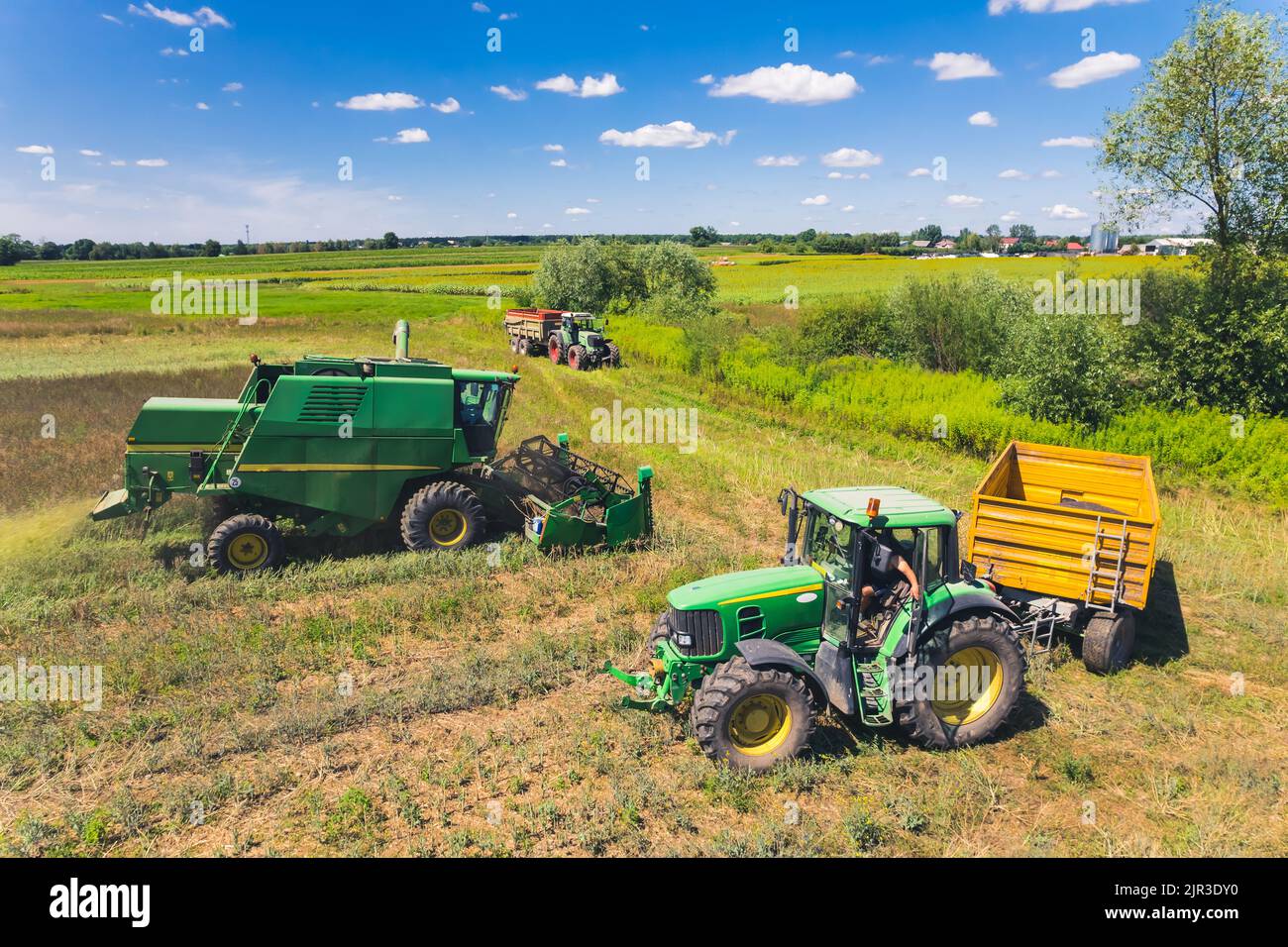 Vista aérea de tres máquinas agrícolas diferentes: Tractor, cosechadora, remolques, utilizadas por los operadores durante la cosecha. Tiempo soleado. . Fotografía de alta calidad Foto de stock