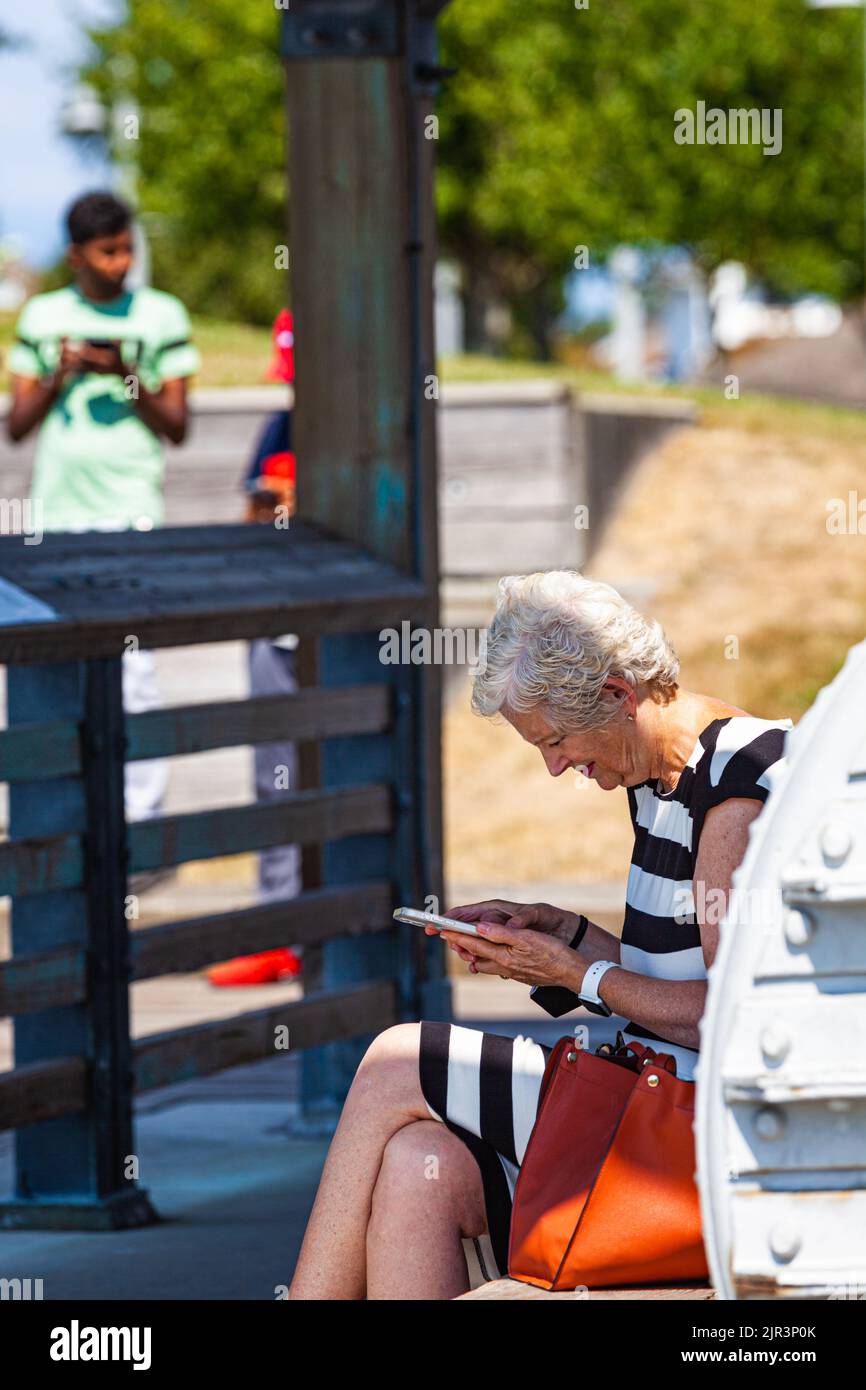 Mujer mayor comprobando su teléfono en el Steveston Maritime Festival en British Columbia, Canadá Foto de stock