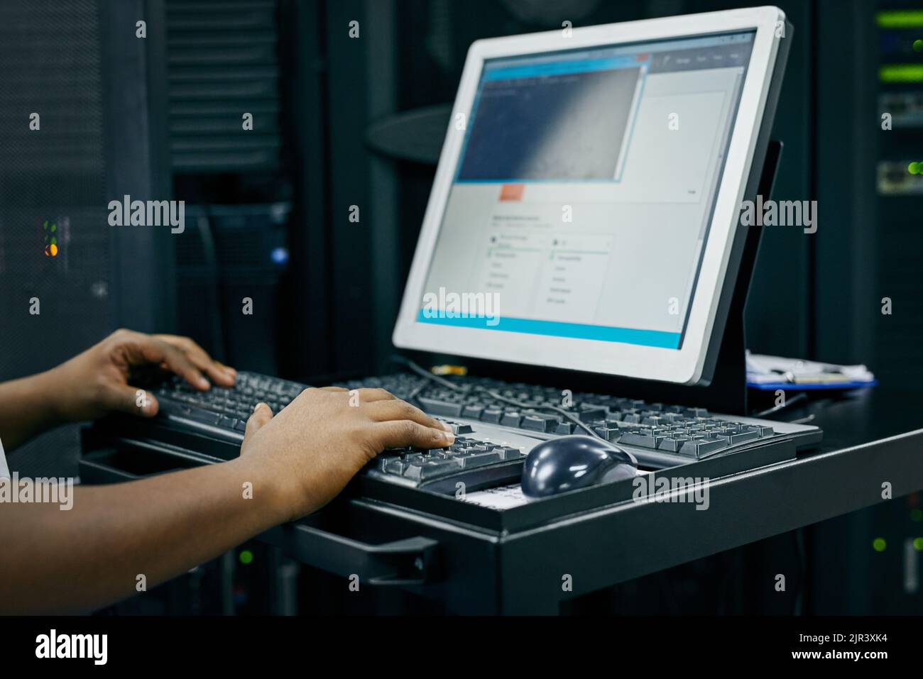 Su red informática en manos expertas. Un técnico DE TI que utiliza un ordenador mientras trabaja en un centro de datos. Foto de stock