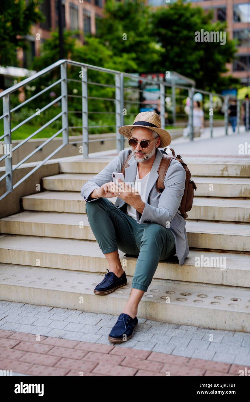 Hombre seguro con sombrero de paja y mochila, uso del teléfono, hombre de  negocios con ropa informal en verano de camino al trabajo Fotografía de  stock - Alamy