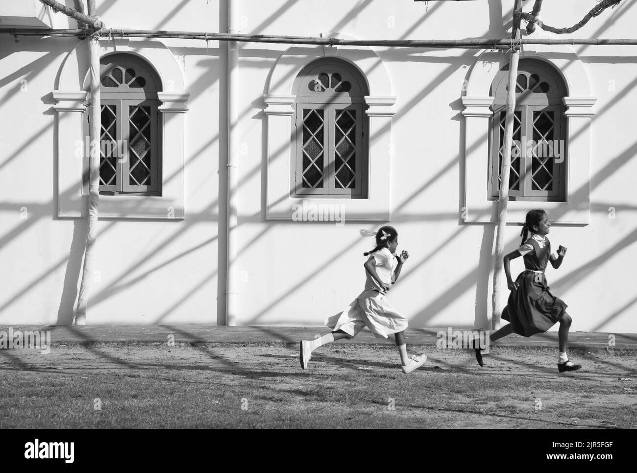 Fort Kochi, Kerala, India - 10 de octubre de 2011: Dos niñas estudiantes indios corriendo a lo largo de la Basílica Santa Cruz después de clase Foto de stock