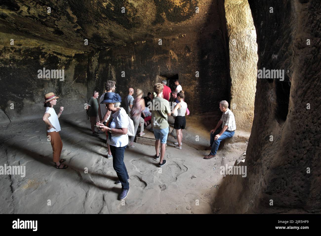 Grupo de turistas escuchando al guía turístico en un sitio arqueológico de Sicilia, Italia Foto de stock