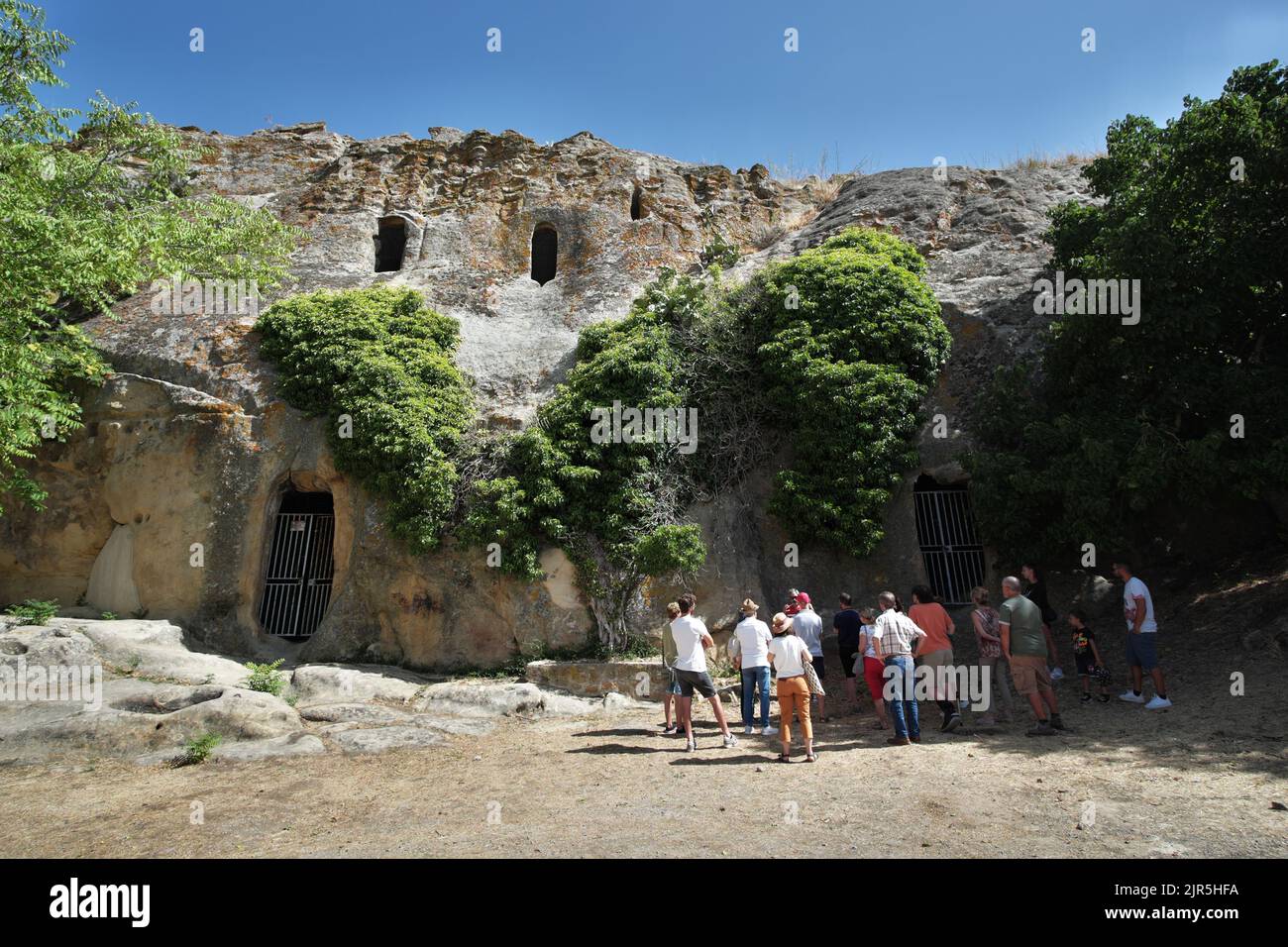 Grupo de turistas escuchando al guía turístico en un sitio arqueológico de Sicilia, Italia Foto de stock