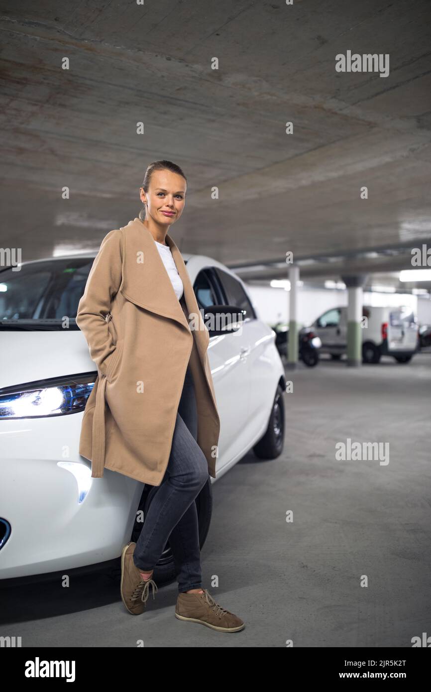 Estacionamiento subterráneo/garaje (DOF poco profundo; imagen en tonos de color) - mujer joven con su coche en el estacionamiento subterráneo Foto de stock