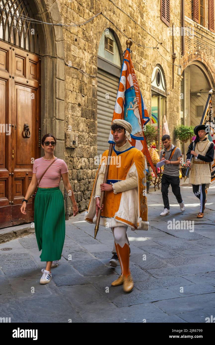 Hombre vestido con traje medieval y con bandera de uno de los Contrada en Via di Città en Siena, Toscana, Italia Foto de stock