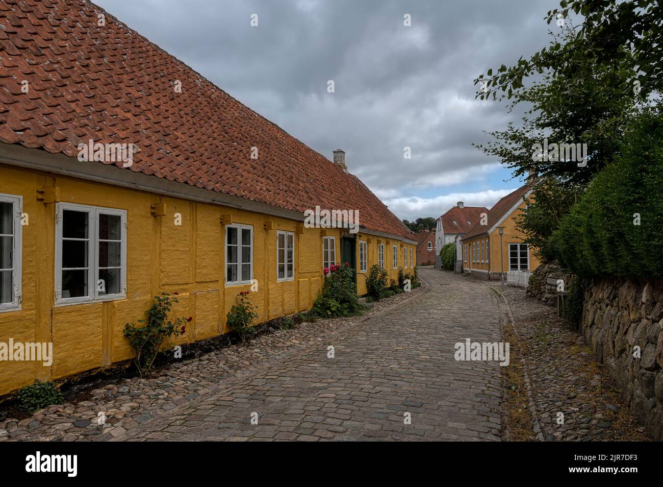 Amarillo entramado de madera pintoresca casa en una calle adoquinada en la ciudad dansih Mariager, Dinamarca, 6 de agosto de 2022 Foto de stock