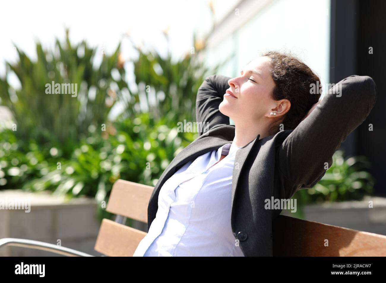 Ejecutivo descansando y relajándose sentado en un banco en un parque Foto de stock