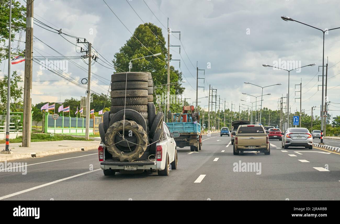 Una camioneta sobrecargada que transporta neumáticos de caucho usados para reciclaje, tomada en Tailandia. Foto de stock