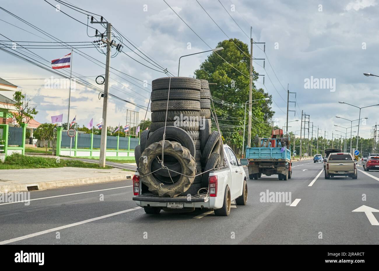 Una camioneta sobrecargada que transporta neumáticos de caucho usados para reciclaje, tomada en Tailandia. Foto de stock