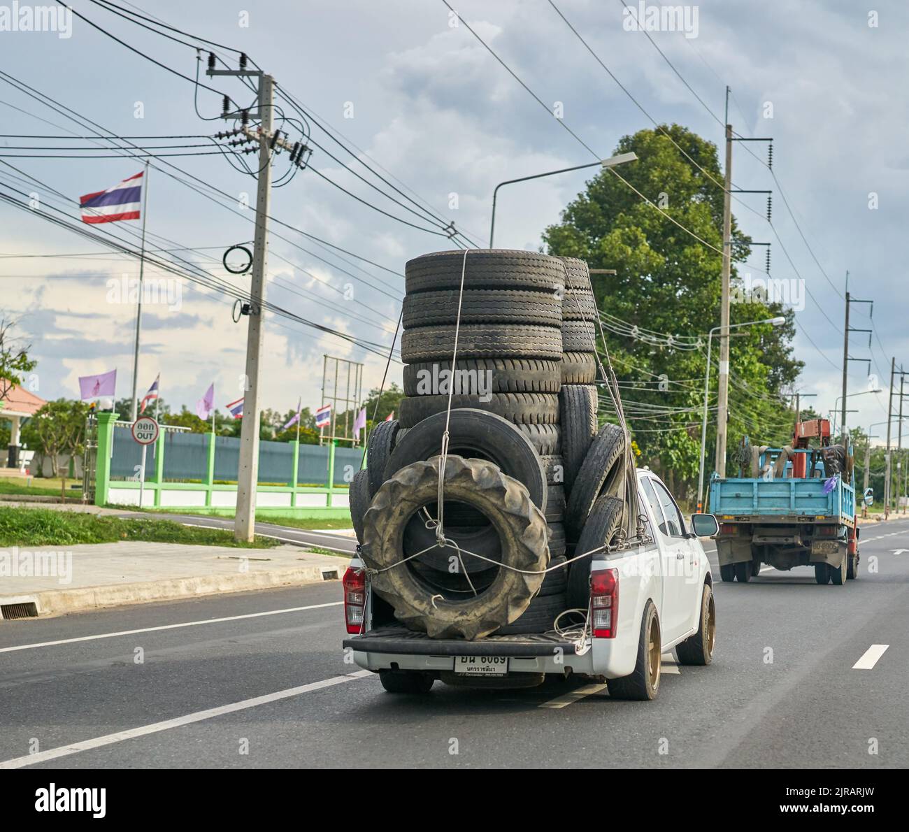 Una camioneta sobrecargada que transporta neumáticos de caucho usados para reciclaje, tomada en Tailandia. Foto de stock