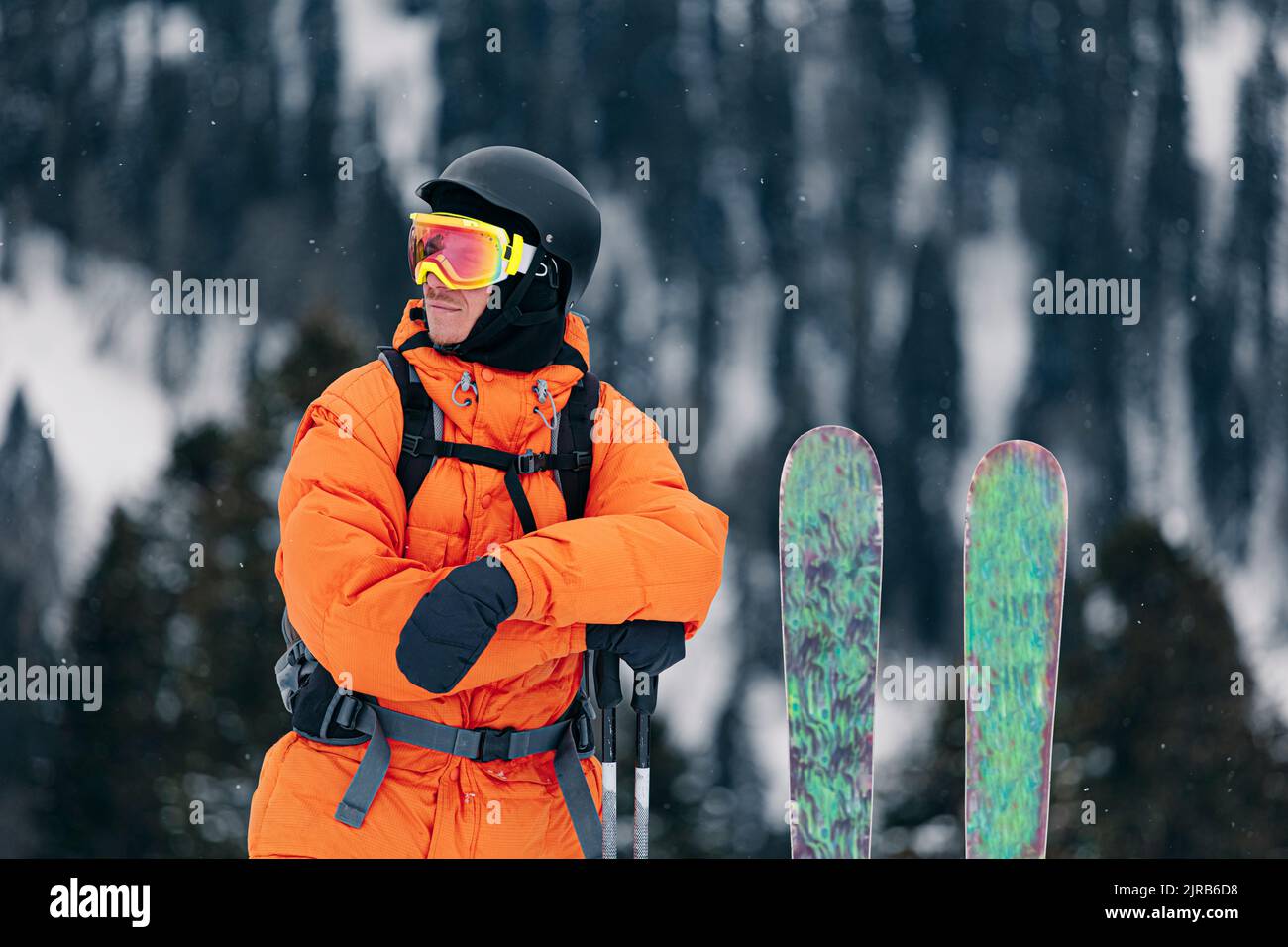 Mujer con ropa de esquí con casco y gafas de esquí en la cabeza con bastones