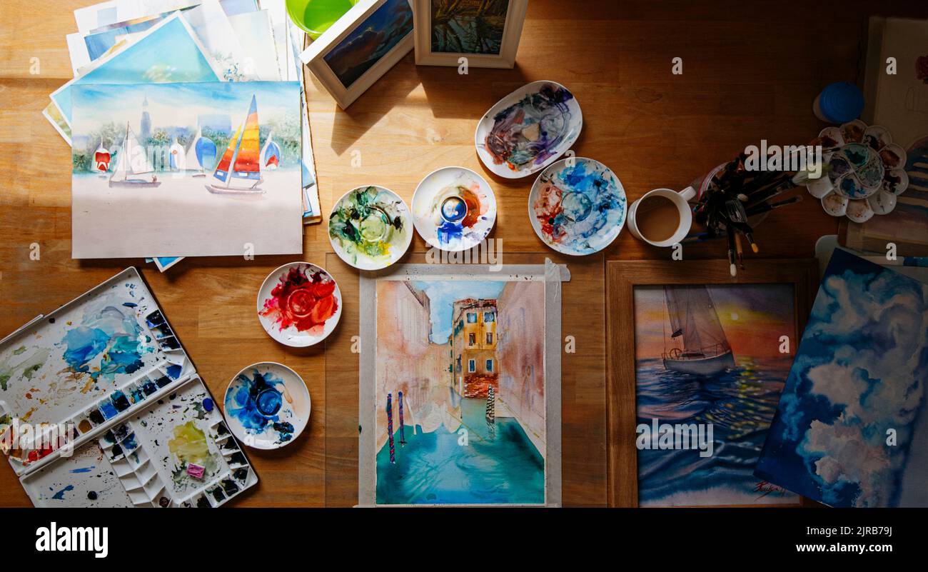 Pintura de acuarela y paletas de colores desordenados sobre la mesa Foto de stock