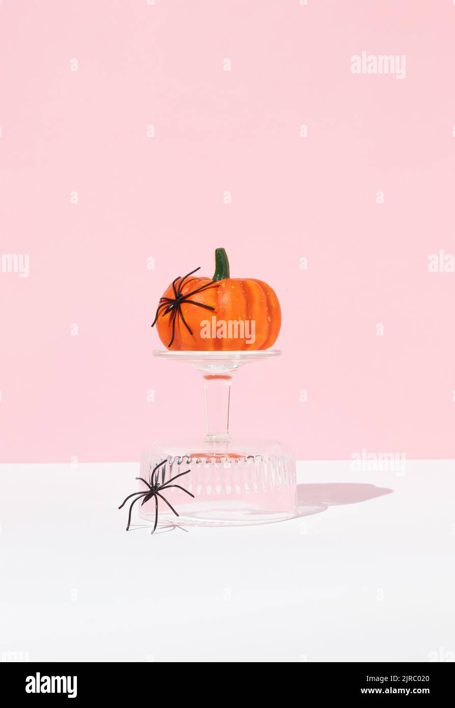 Composición creativa de Halloween hecha de calabaza sobre podio de cristal con arañas. Concepto de vacaciones mínimas. Estética rosa. Foto de stock