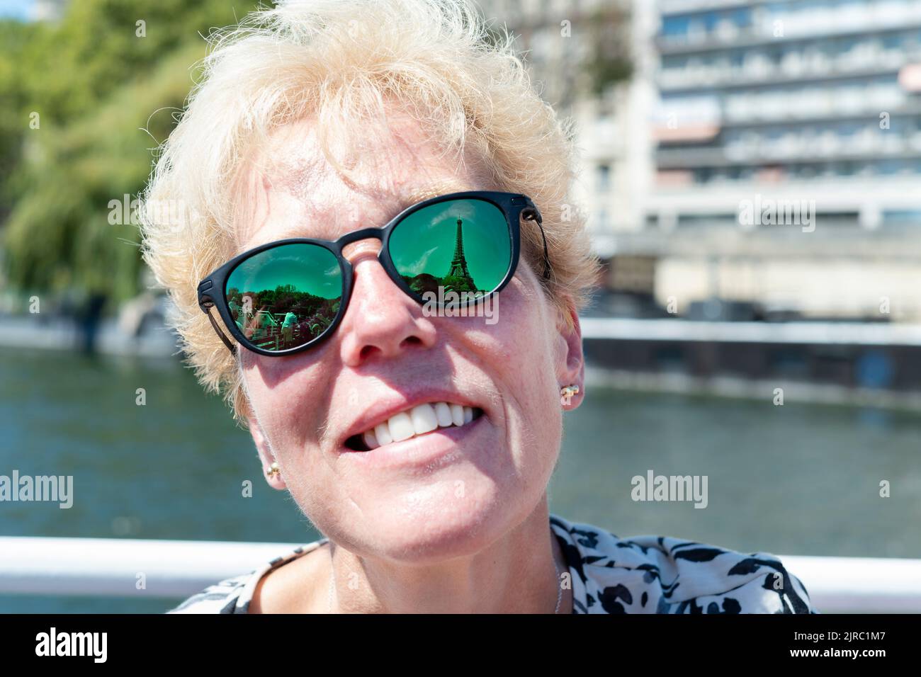 Una turista mujer que visita París, Francia mira hacia arriba la Torre Eiffel. El famoso monumento se refleja en las gafas de sol Oakley Woman's prescription Foto de stock