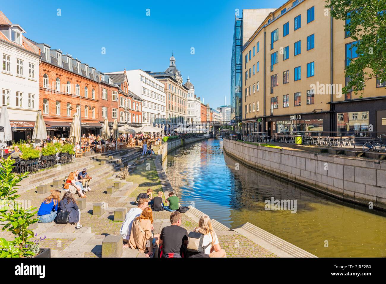 La gente se reúne en terrazas para comer y beber en el centro de la ciudad a lo largo del río Aarhus en un día de verano en Aarhus, Dinamarca Foto de stock