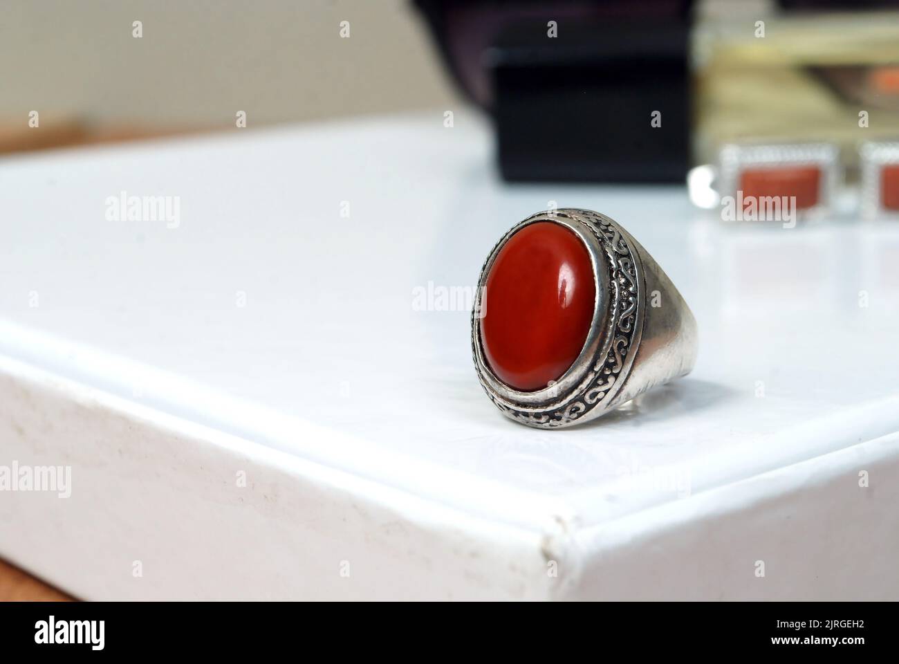 hombres anillo de piedra espiritual aislado en blanco macro enfoque borroso fondo rojo piedra preciosa primer plano Foto de stock