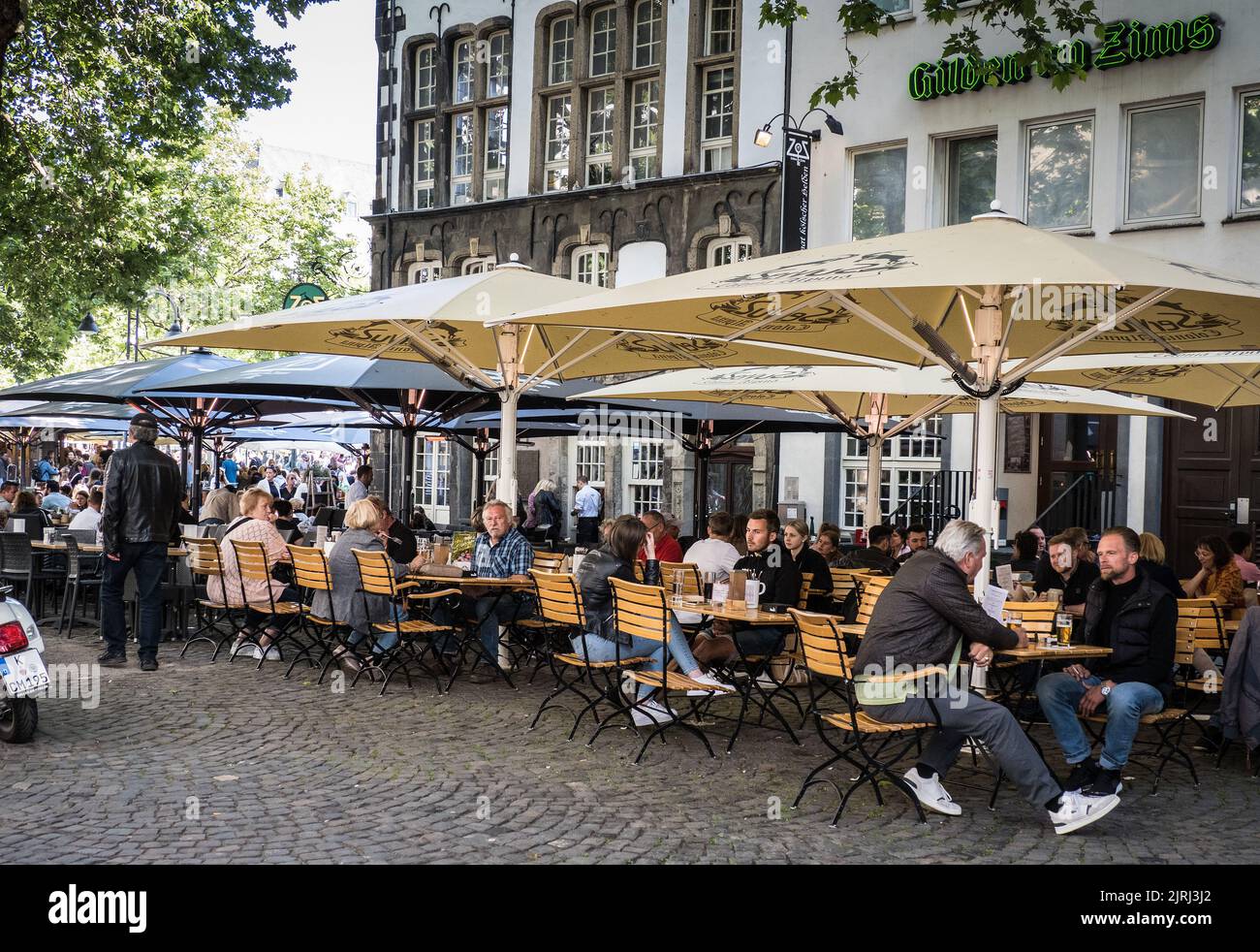 Los lugareños disfrutan sentados y bebiendo Kolsch al aire libre en una brauhaus de Colonia Foto de stock