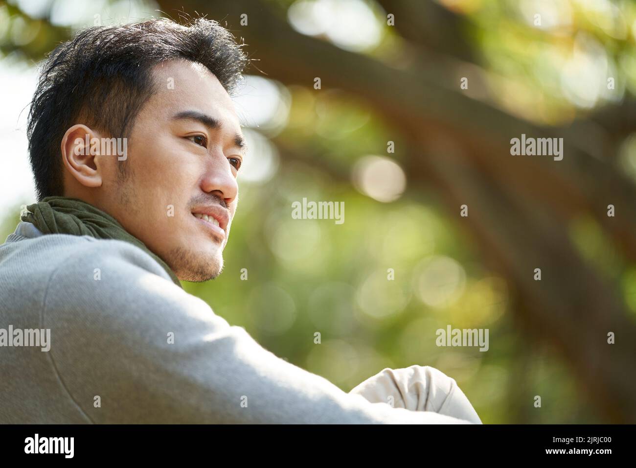 retrato al aire libre de un joven asiático adulto, vista lateral Foto de stock