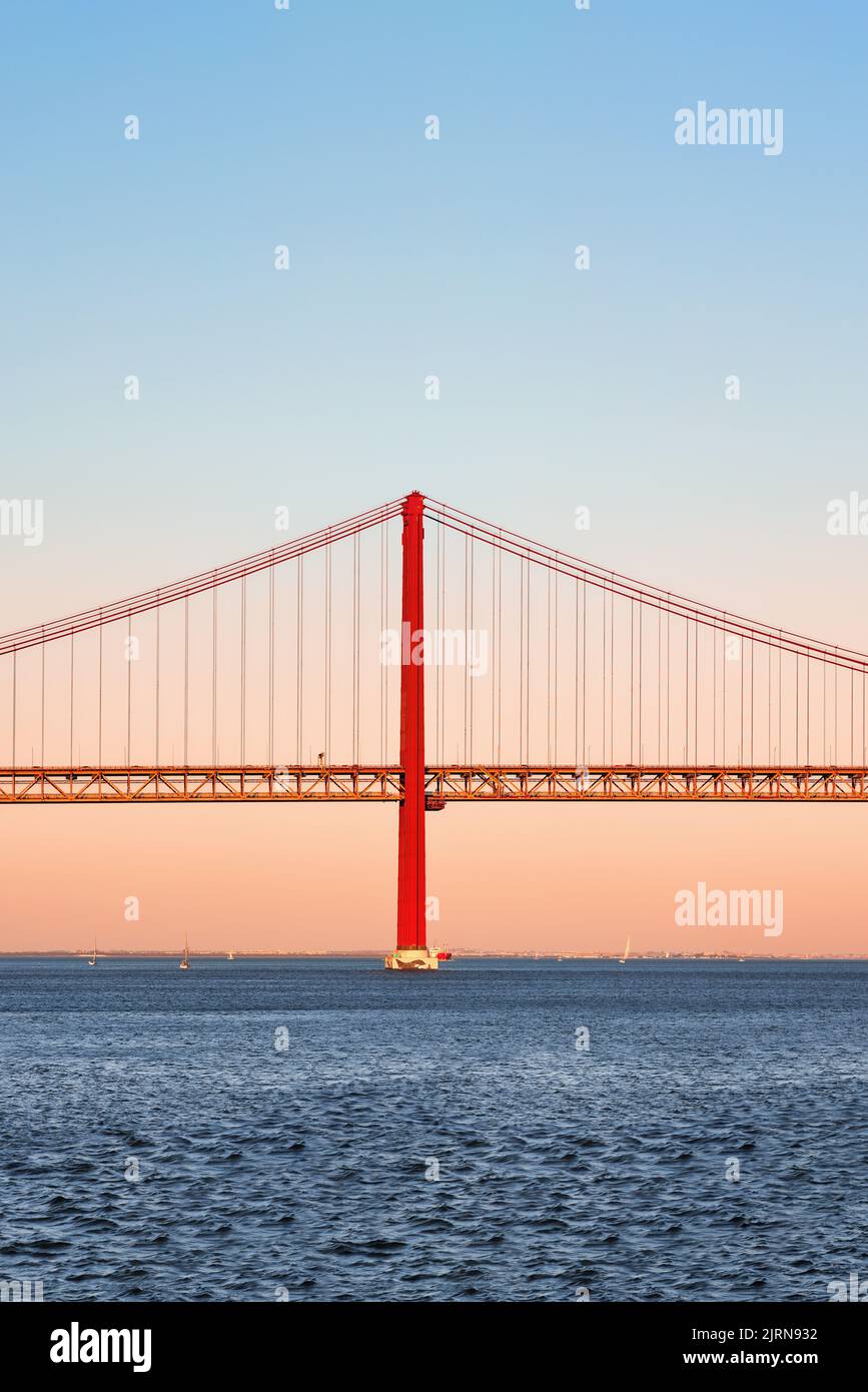 Icónico puente colgante naranja y rojo sobre el río Tajo en Lisboa, Portugal. Puente 25 de Abril, 25th de Abril Puente a la hora dorada del atardecer. Espacio de copia. Foto de stock