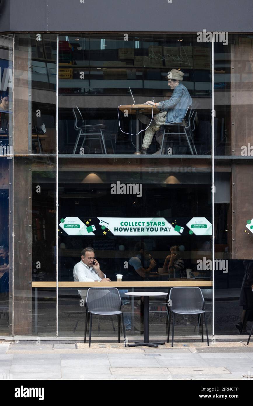 Personas sentadas en una cafetería londinense en dos niveles diferentes, Inglaterra, Reino Unido Foto de stock
