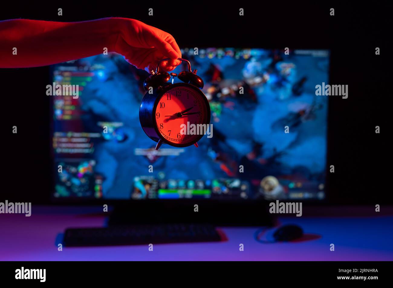 Mujer sosteniendo un reloj despertador en el fondo de un juego de  computadora en el monitor Fotografía de stock - Alamy