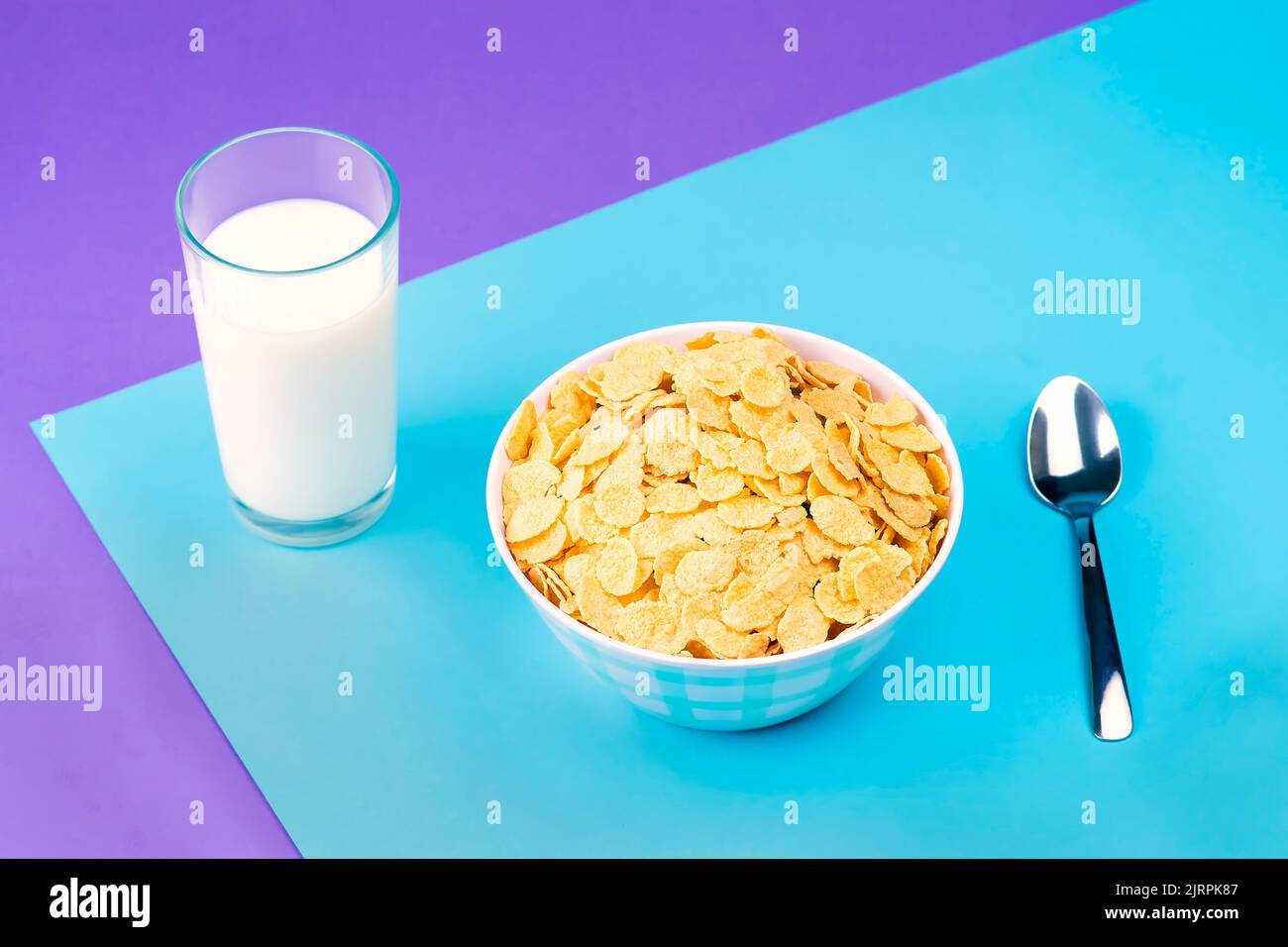 Vista de un plato con cereal natural y un vaso de leche fresca sobre un fondo de colores pastel. Foto de stock