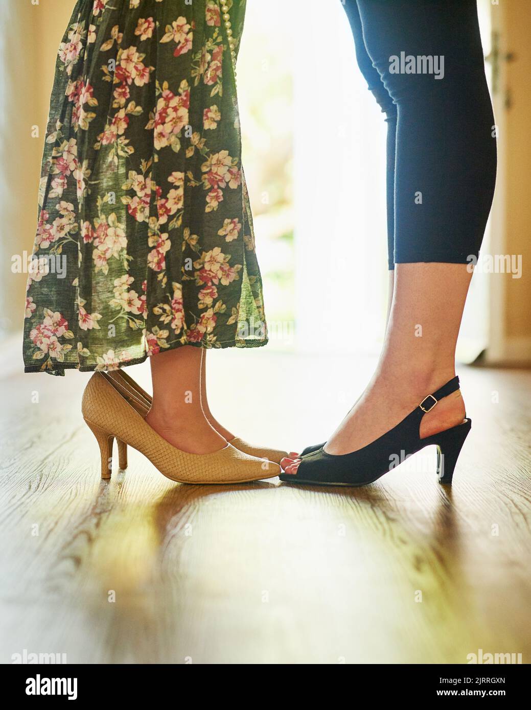 Shell seguir los pasos de las mamás. Una madre y su hija pequeña usando tacones altos en casa. Foto de stock