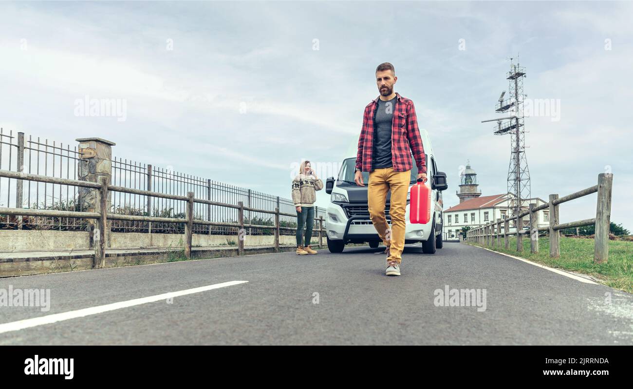Hombre con jerrycan caminando buscando ayuda para su campervan roto Foto de stock
