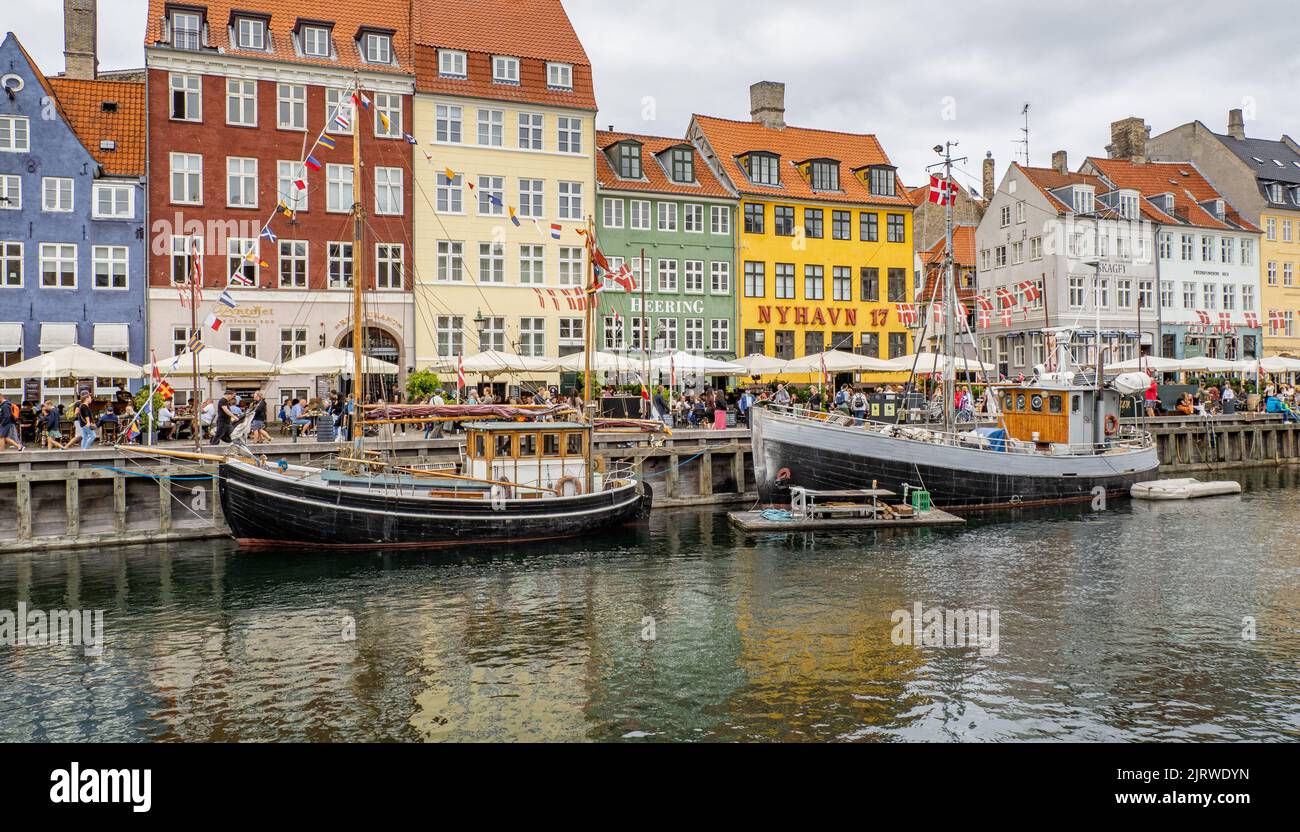 El destino turístico popular de Nyhavn una ensenada del mar bordeada de 17th C casas de colores cafés y bares y barcos de vela - Copenhague Dinamarca Foto de stock