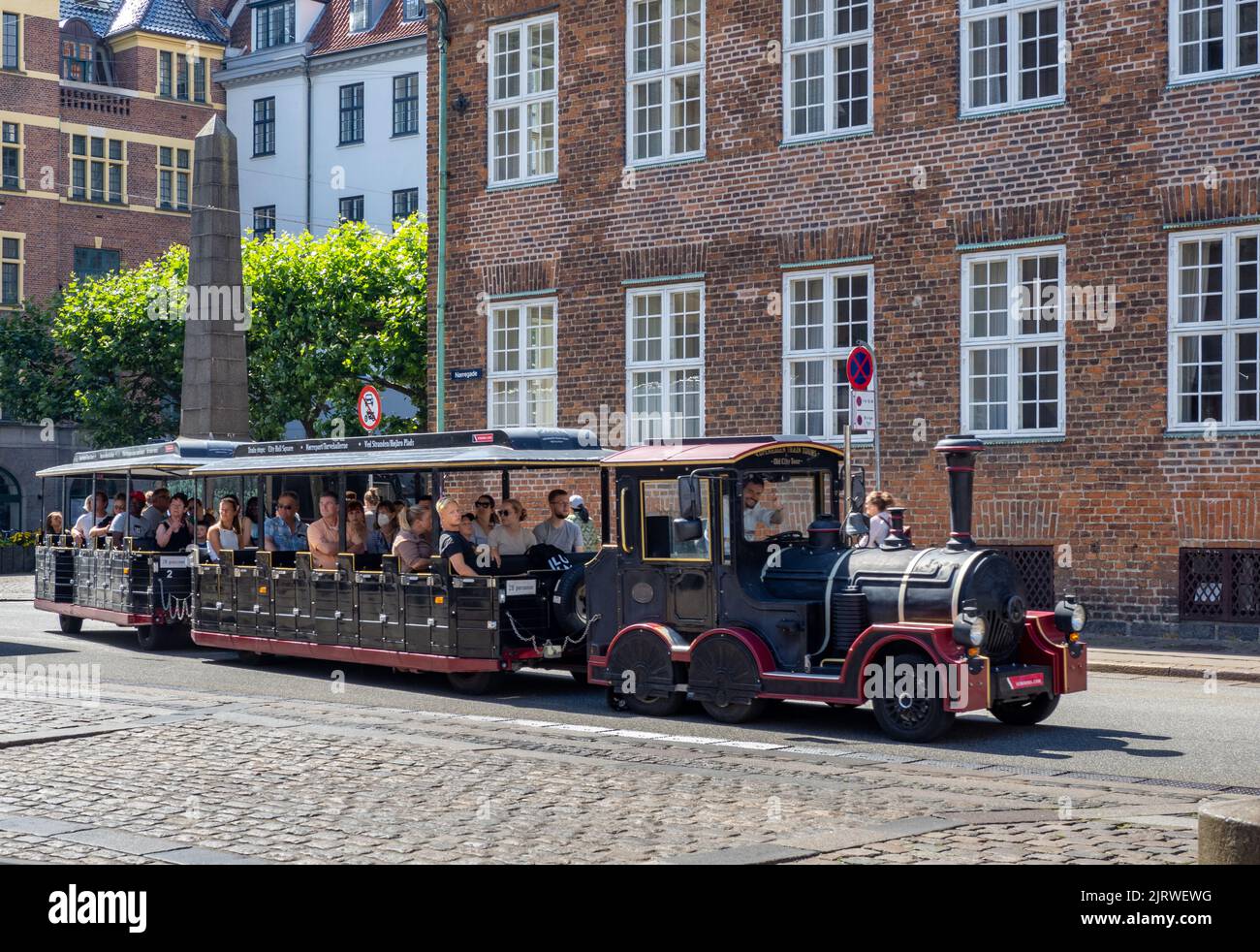 Tren turístico con conductor alegre que lleva a los visitantes en una visita guiada por las calles de Copenhague, Dinamarca Foto de stock