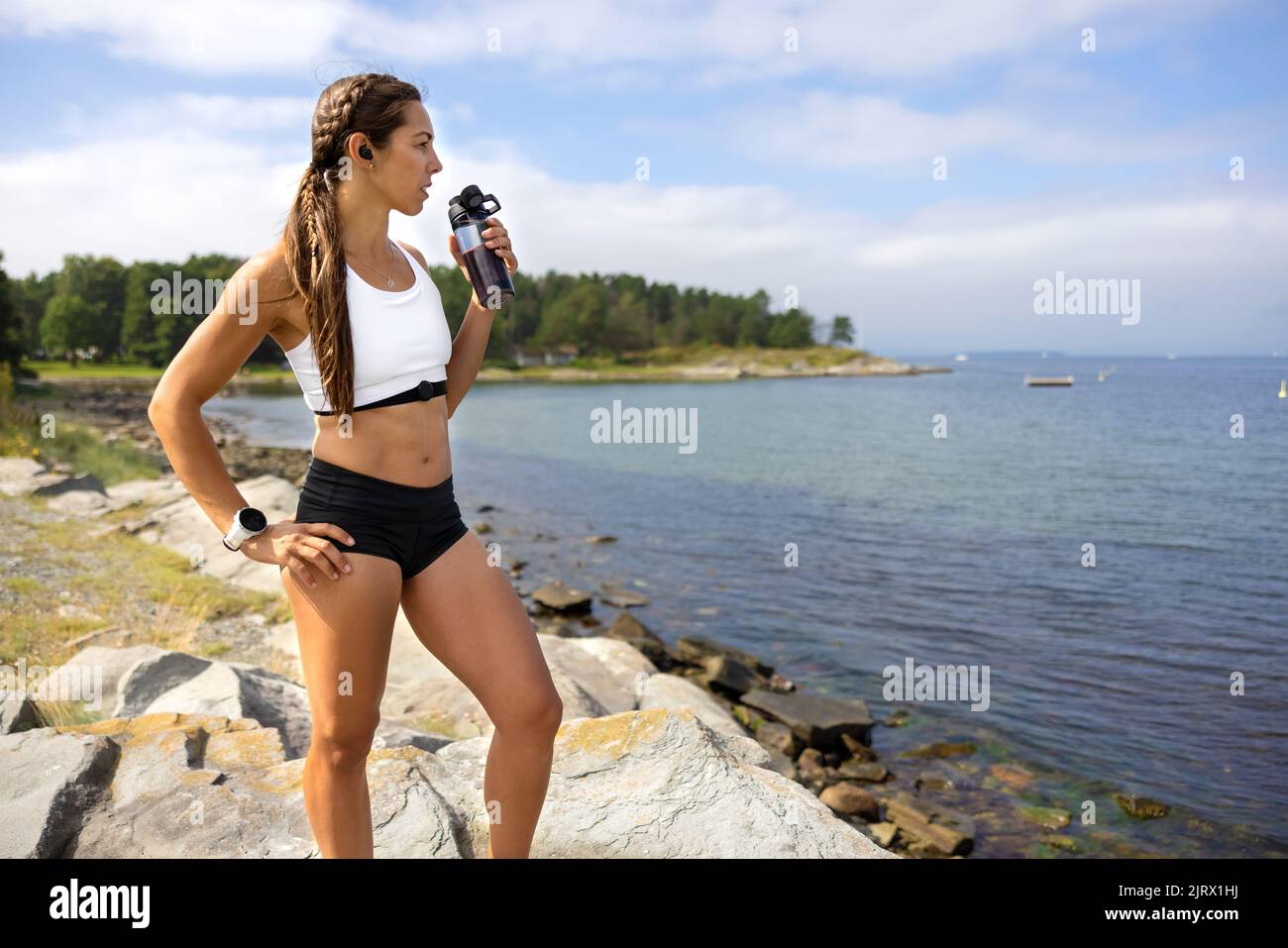 Atleta con la mano en la cadera beber agua durante el entrenamiento Foto de stock