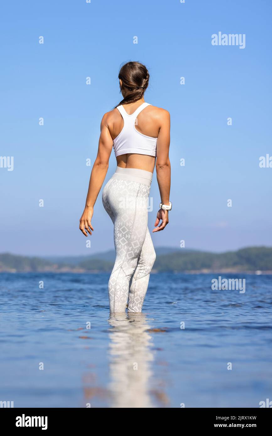 Mujer atlética de pie en el mar contra el cielo despejado Foto de stock
