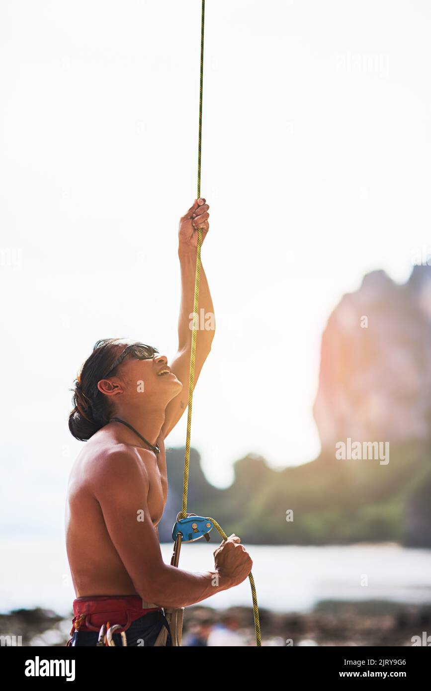 Subir es donde seguirá. Un joven escalando una montaña en un día soleado. Foto de stock