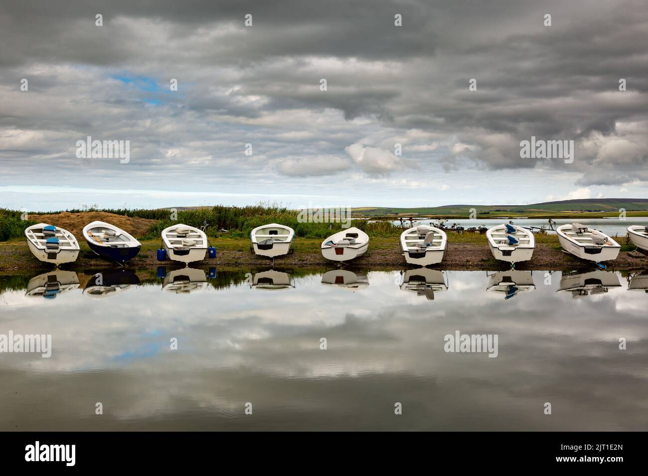 Loch Harray, Orkney, Reino Unido. 27th de Ago de 2022. Los botes se reflejan en las tranquilas aguas de Loch Harray, Orkney continental, Reino Unido. Los barcos son utilizados por los entusiastas locales de la pesca con mosca. Crédito: Peter Lopeman/Alamy Live News Foto de stock